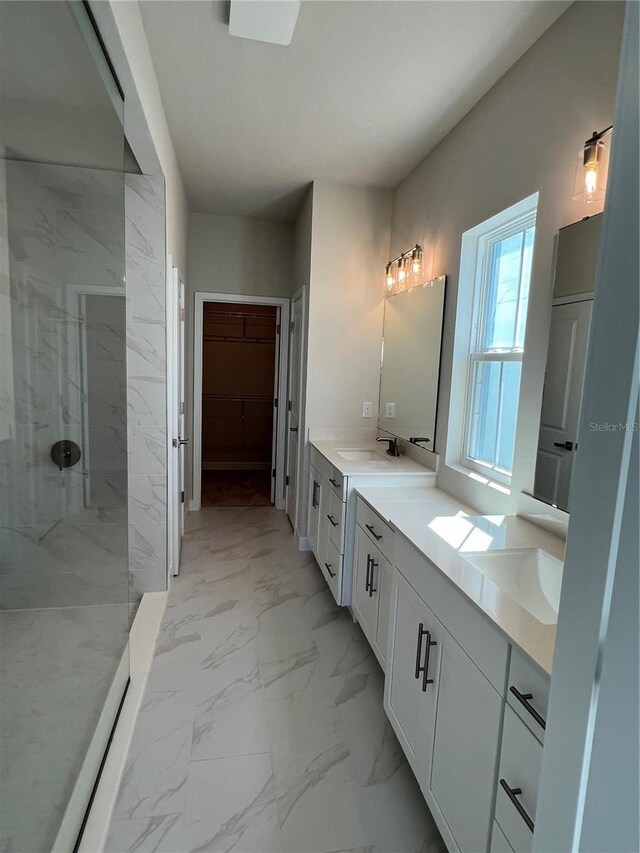 bathroom with marble finish floor, a spacious closet, a marble finish shower, and vanity