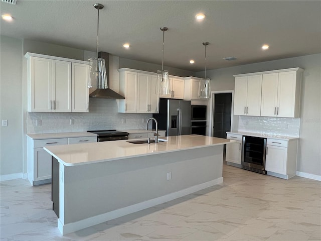 kitchen with marble finish floor, appliances with stainless steel finishes, a sink, beverage cooler, and wall chimney exhaust hood