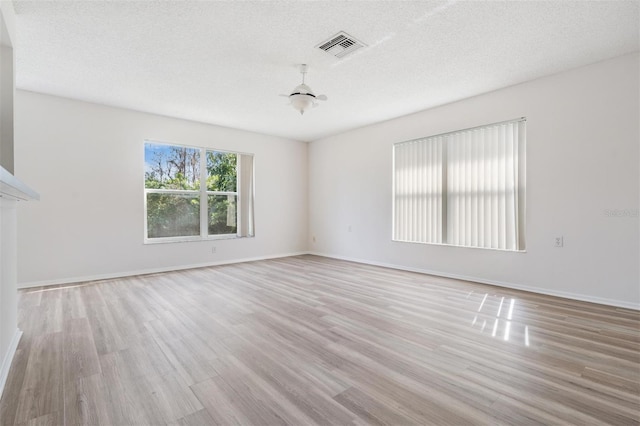 spare room featuring light hardwood / wood-style floors and a textured ceiling