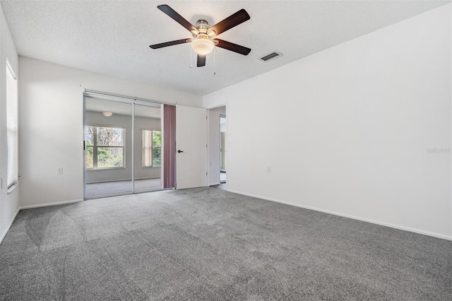 carpeted spare room with ceiling fan and a textured ceiling