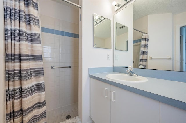 bathroom featuring walk in shower, vanity, and a textured ceiling