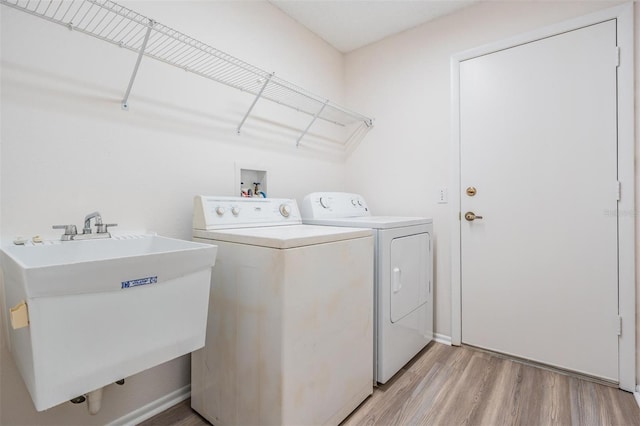 laundry room with light hardwood / wood-style flooring, sink, and washer and clothes dryer