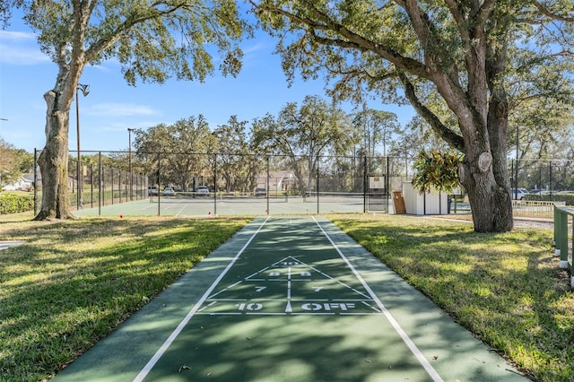 view of property's community with a yard and tennis court