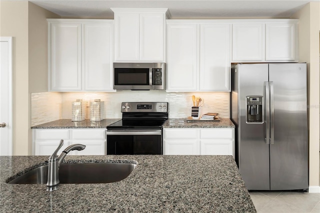 kitchen featuring white cabinetry, stainless steel appliances, sink, and dark stone counters