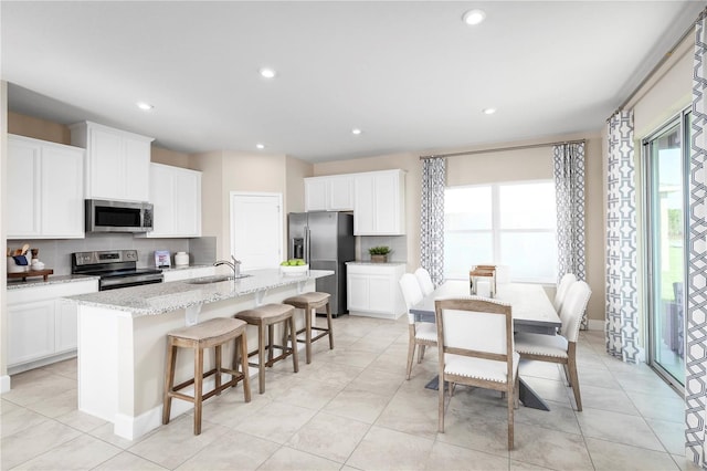 kitchen featuring sink, a center island with sink, a breakfast bar area, and appliances with stainless steel finishes