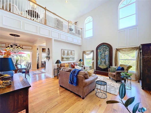 living room with an inviting chandelier, a towering ceiling, and light hardwood / wood-style flooring