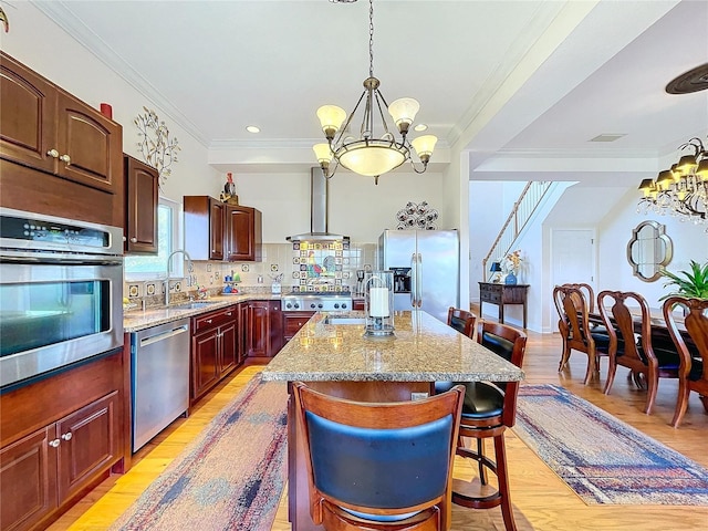 kitchen featuring stainless steel appliances, decorative light fixtures, a chandelier, and wall chimney range hood