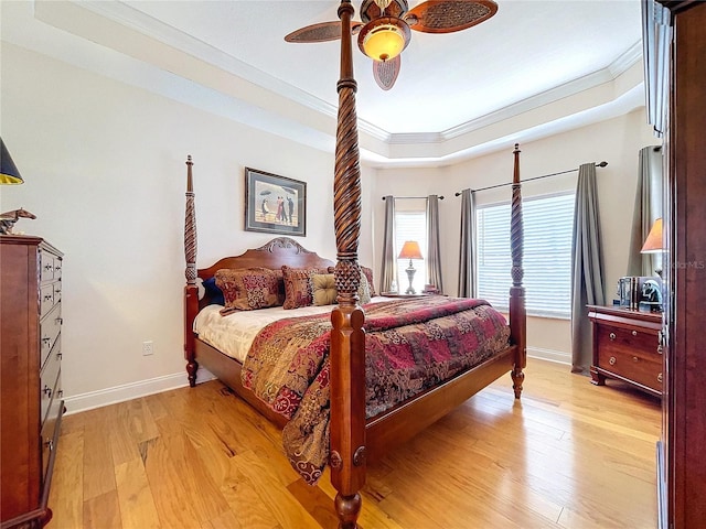 bedroom with crown molding, ceiling fan, light wood-type flooring, and a tray ceiling