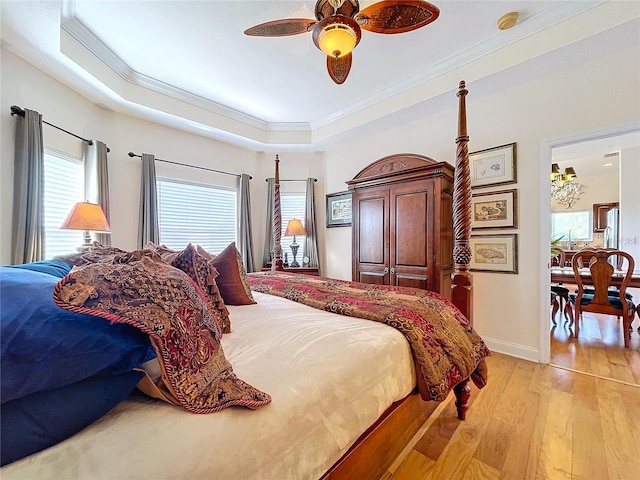 bedroom with a raised ceiling, ornamental molding, ceiling fan, and light wood-type flooring