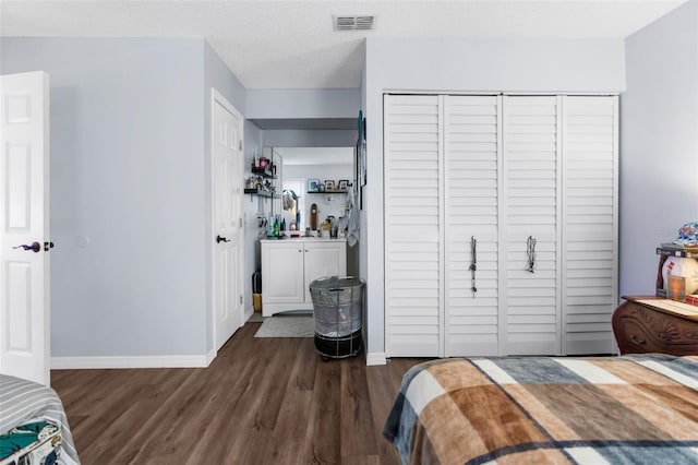 bedroom featuring a closet, dark hardwood / wood-style floors, and a textured ceiling