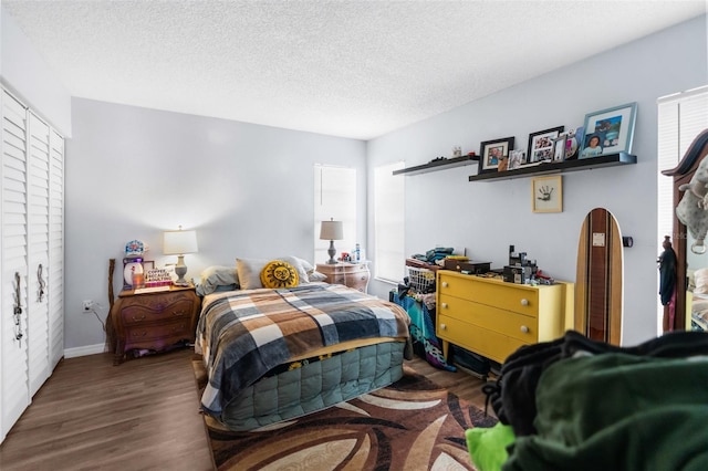 bedroom featuring multiple windows, dark hardwood / wood-style floors, and a textured ceiling