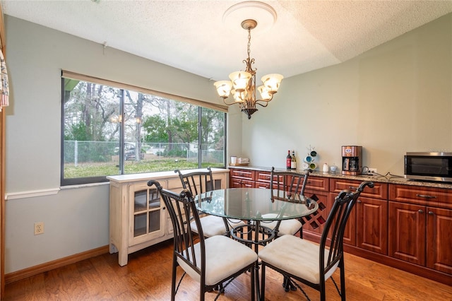 dining area featuring lofted ceiling, a chandelier, a textured ceiling, and light hardwood / wood-style flooring