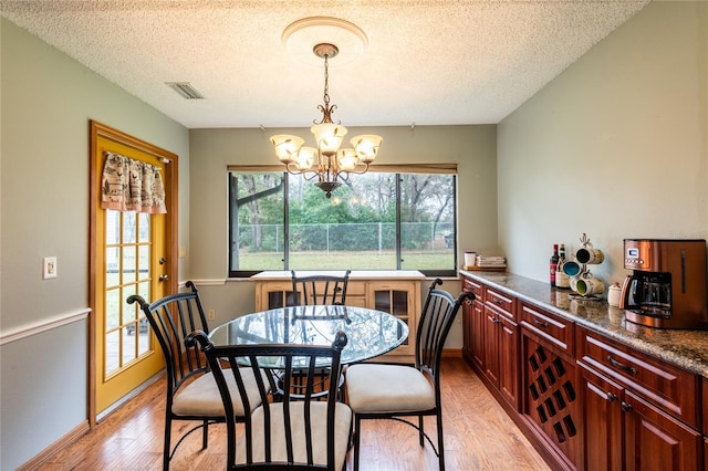 dining space featuring a chandelier, a textured ceiling, and light wood-type flooring