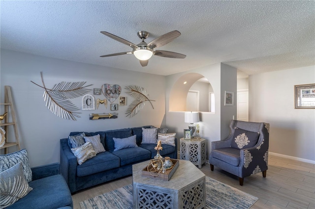 living room featuring ceiling fan, wood-type flooring, and a textured ceiling