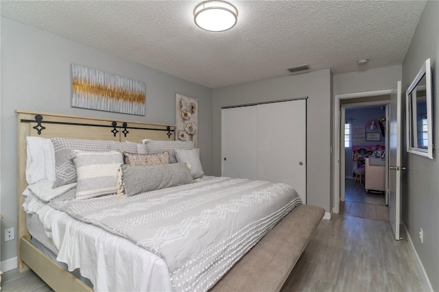 bedroom featuring light hardwood / wood-style flooring, a textured ceiling, and a closet