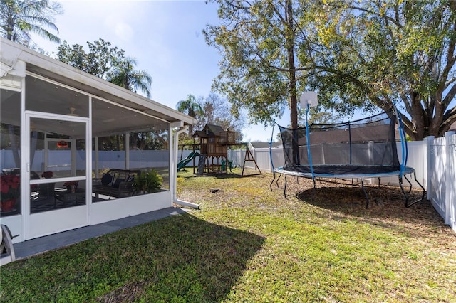 view of yard featuring a sunroom, a playground, and a trampoline