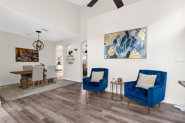 sitting room with wood-type flooring and ceiling fan with notable chandelier