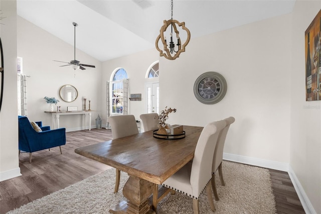 dining room featuring ceiling fan with notable chandelier, hardwood / wood-style floors, and high vaulted ceiling