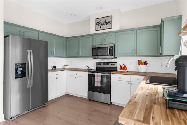 kitchen with appliances with stainless steel finishes, sink, white cabinets, and butcher block countertops