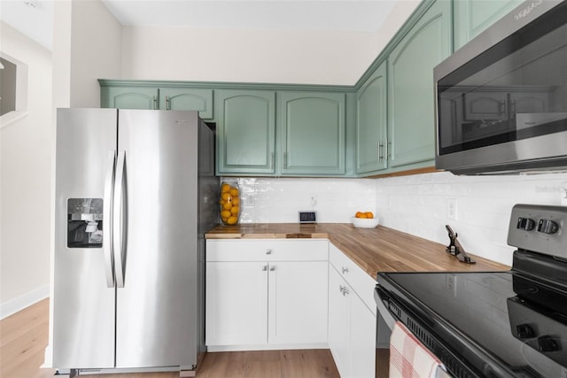 kitchen with tasteful backsplash, green cabinetry, wooden counters, light wood-type flooring, and stainless steel appliances