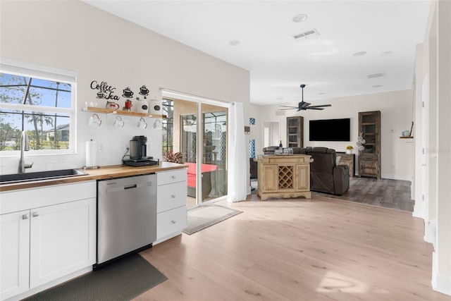 kitchen featuring white cabinetry, dishwasher, butcher block counters, sink, and a healthy amount of sunlight