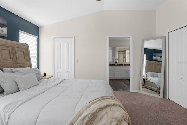 bedroom with vaulted ceiling, carpet flooring, and connected bathroom