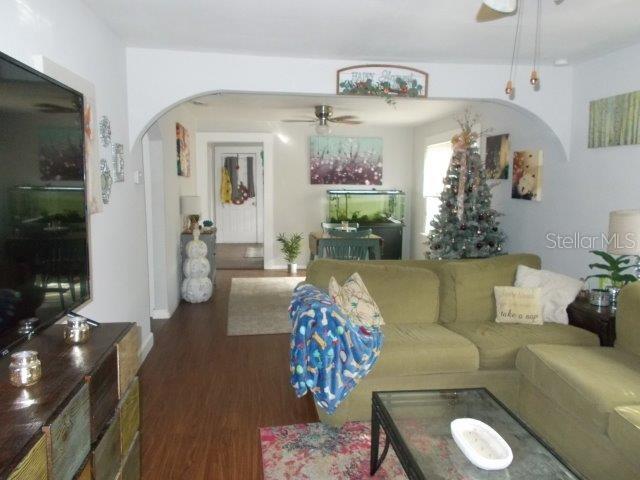 living room with dark wood-type flooring and ceiling fan