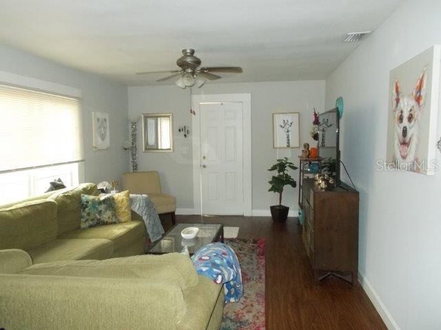 living room featuring ceiling fan and dark hardwood / wood-style floors