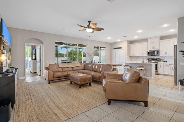 living room with light tile patterned flooring, ceiling fan, and sink