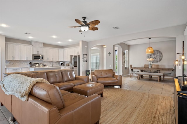 tiled living room with ceiling fan and sink