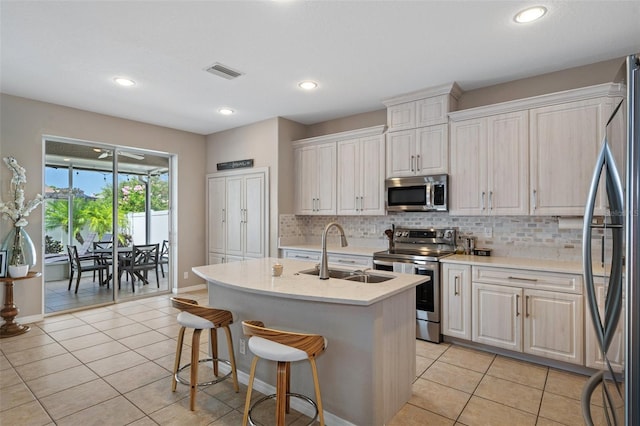 kitchen featuring stainless steel appliances, a kitchen island with sink, sink, and white cabinets