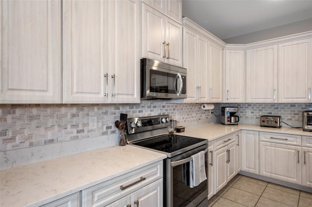 kitchen featuring white cabinetry, backsplash, light tile patterned flooring, and appliances with stainless steel finishes