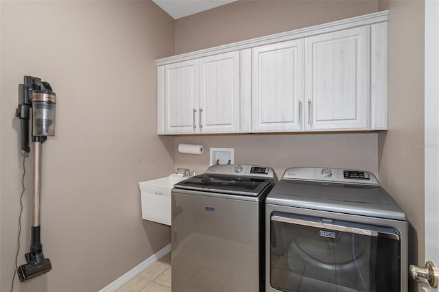 laundry area with cabinets, independent washer and dryer, light tile patterned flooring, and sink