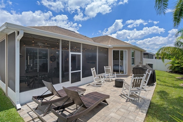 back of property featuring a sunroom, a patio area, and a lawn