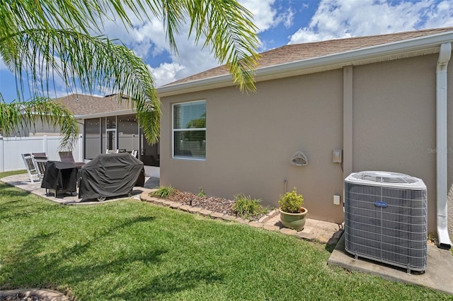 rear view of property with a yard and central air condition unit