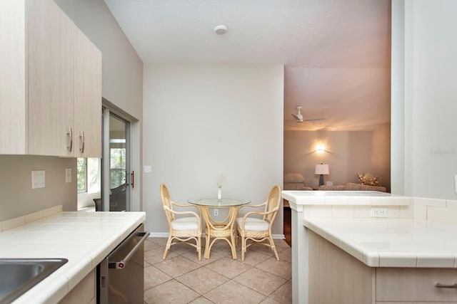 kitchen featuring light brown cabinetry, light tile patterned floors, tile countertops, and dishwasher