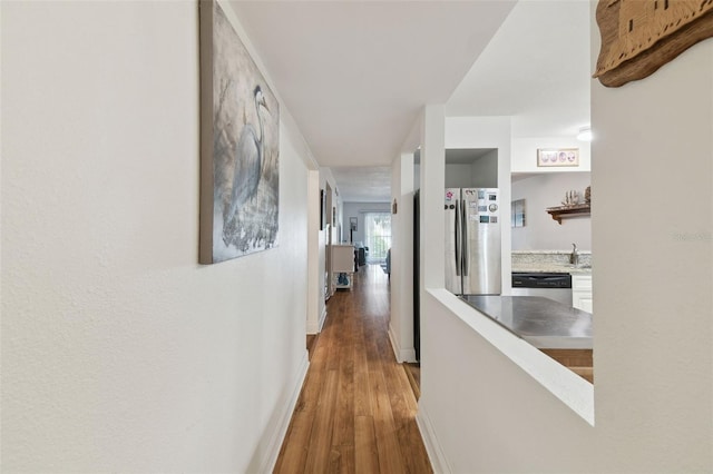 corridor featuring wood-type flooring and sink