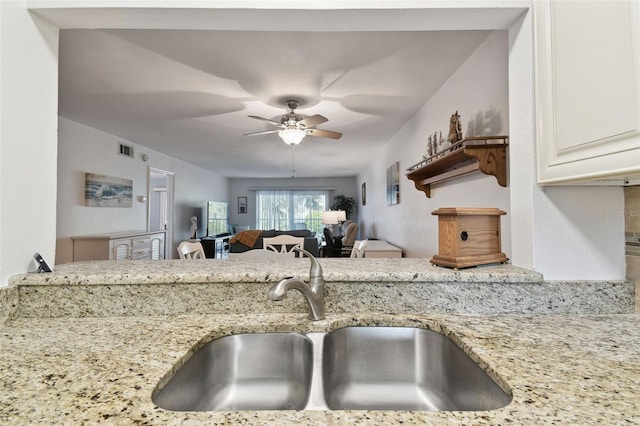 kitchen with light stone counters, sink, and ceiling fan