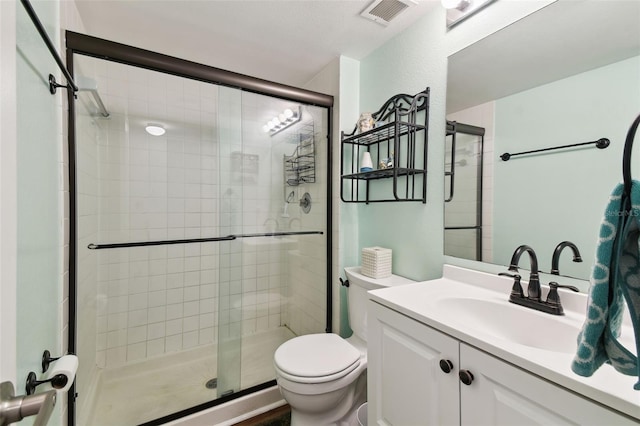 bathroom featuring vanity, a shower with shower door, and toilet