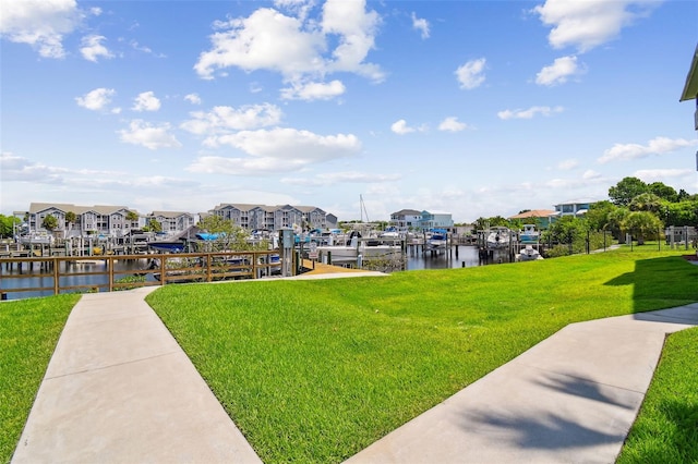 surrounding community featuring a water view, a yard, and a dock