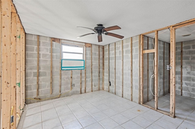 basement with ceiling fan and a textured ceiling