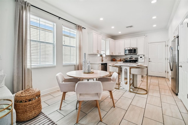 kitchen with sink, crown molding, appliances with stainless steel finishes, white cabinetry, and a kitchen island