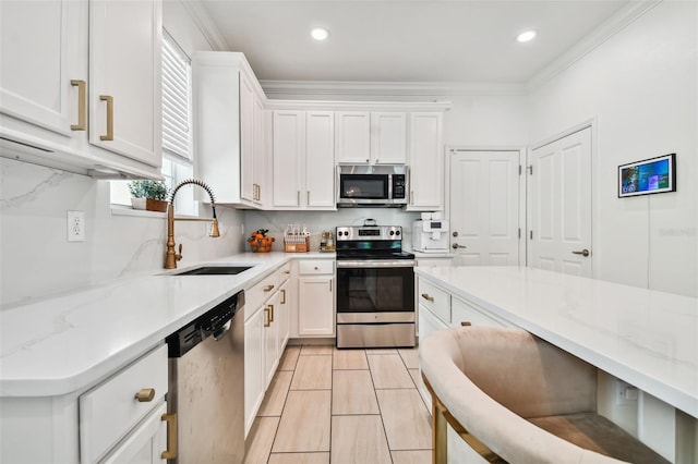 kitchen with light stone counters, appliances with stainless steel finishes, sink, and white cabinets