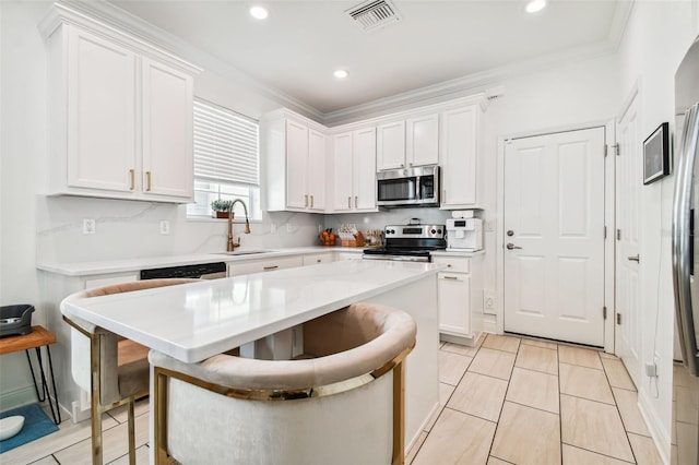 kitchen featuring white cabinetry, appliances with stainless steel finishes, sink, and a kitchen bar