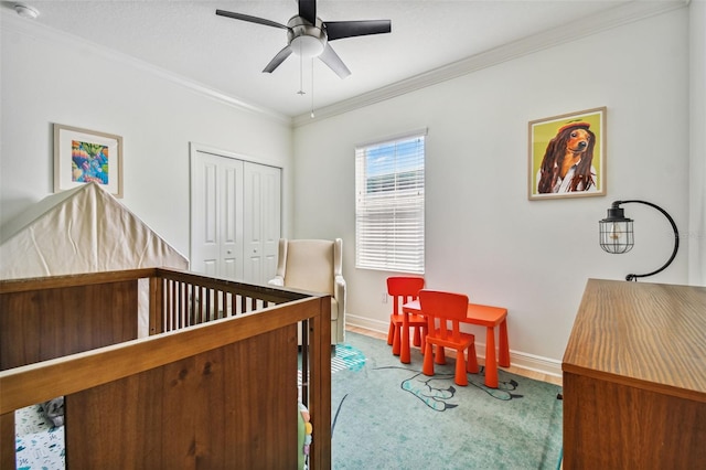 bedroom with crown molding, a nursery area, a closet, and ceiling fan