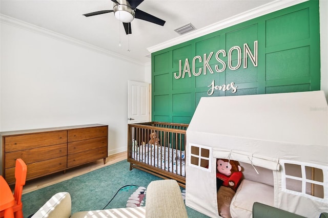 bedroom featuring ornamental molding, a nursery area, and ceiling fan