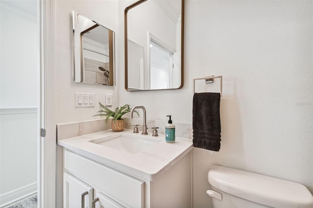 bathroom with vanity, crown molding, and toilet