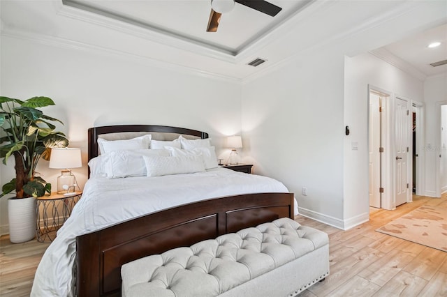 bedroom featuring crown molding, ceiling fan, a tray ceiling, and light hardwood / wood-style floors