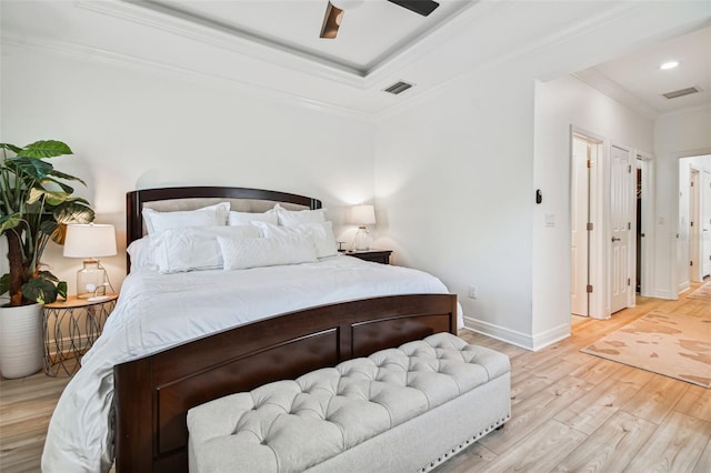 bedroom with ornamental molding, a raised ceiling, ceiling fan, and light wood-type flooring