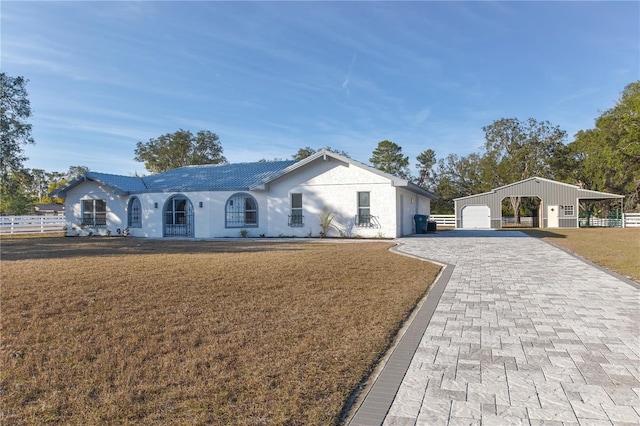 ranch-style house featuring a garage, an outbuilding, and a front lawn